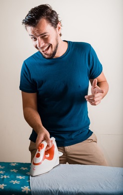 young stylish man housewife ironing